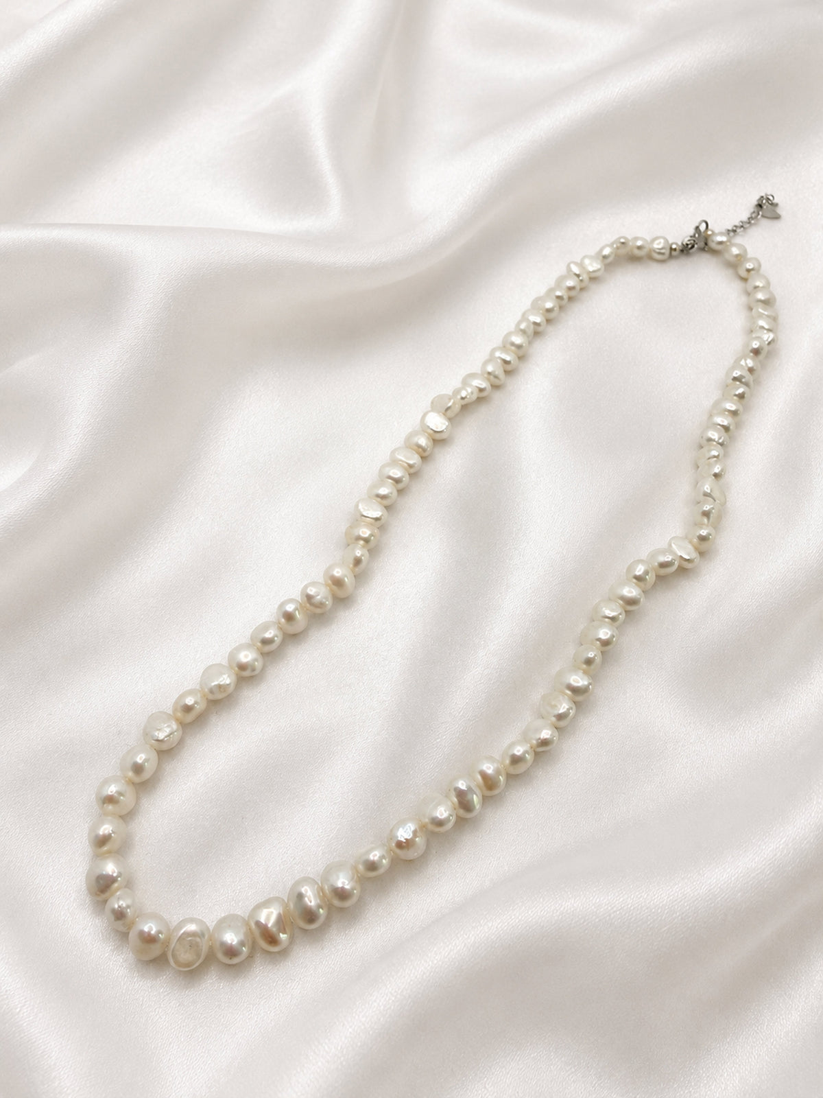 Irregular freshwater pearl necklace — white satin flatlay